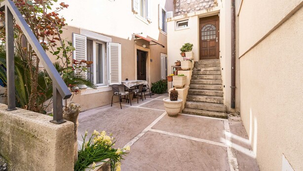 A narrow courtyard with a stone staircase, outdoor seating, and potted plants. - Apartment Family Tokić  (Dubrovnik)