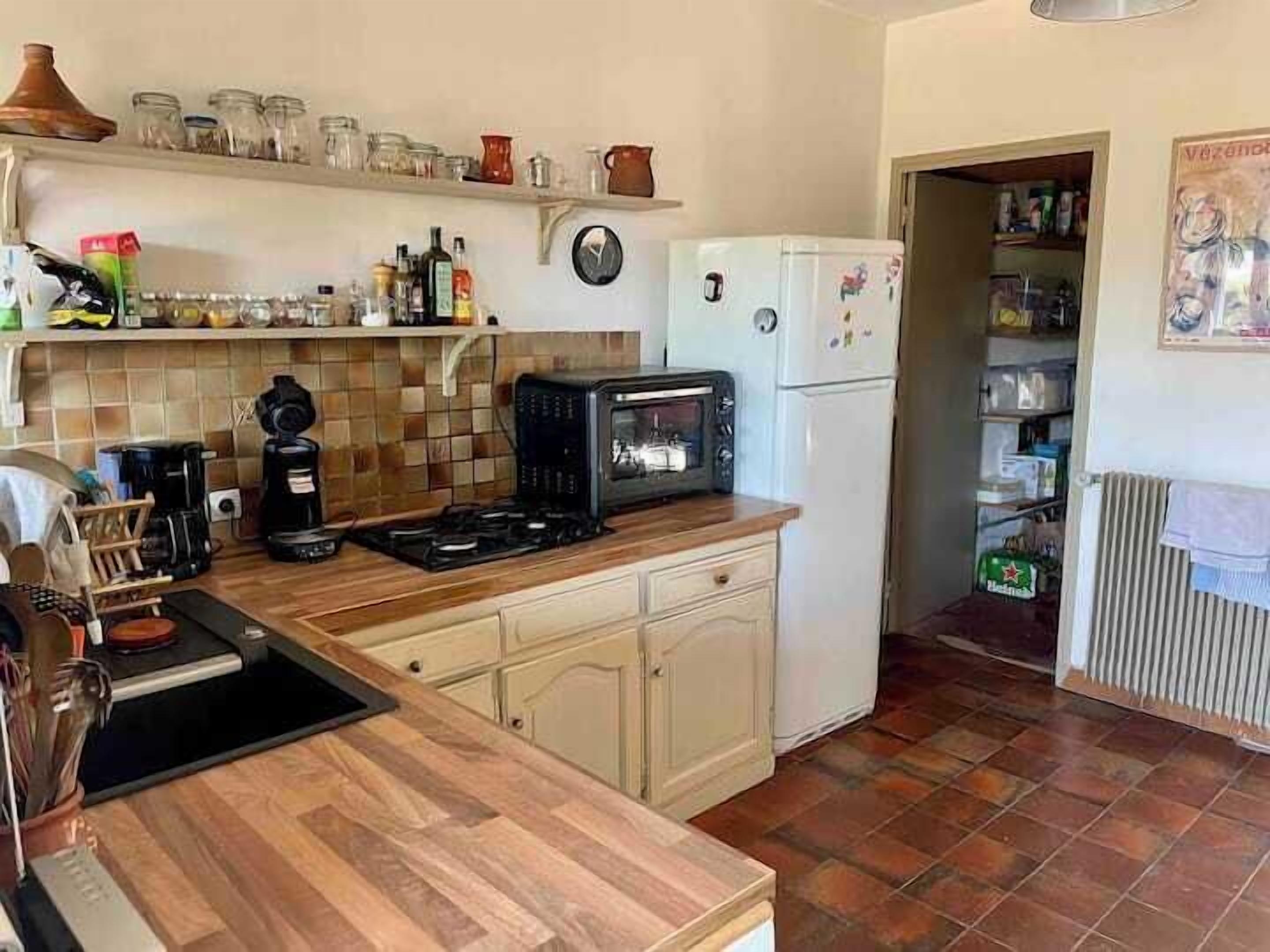 A compact kitchen with a microwave, coffee maker, and a tiled backsplash.