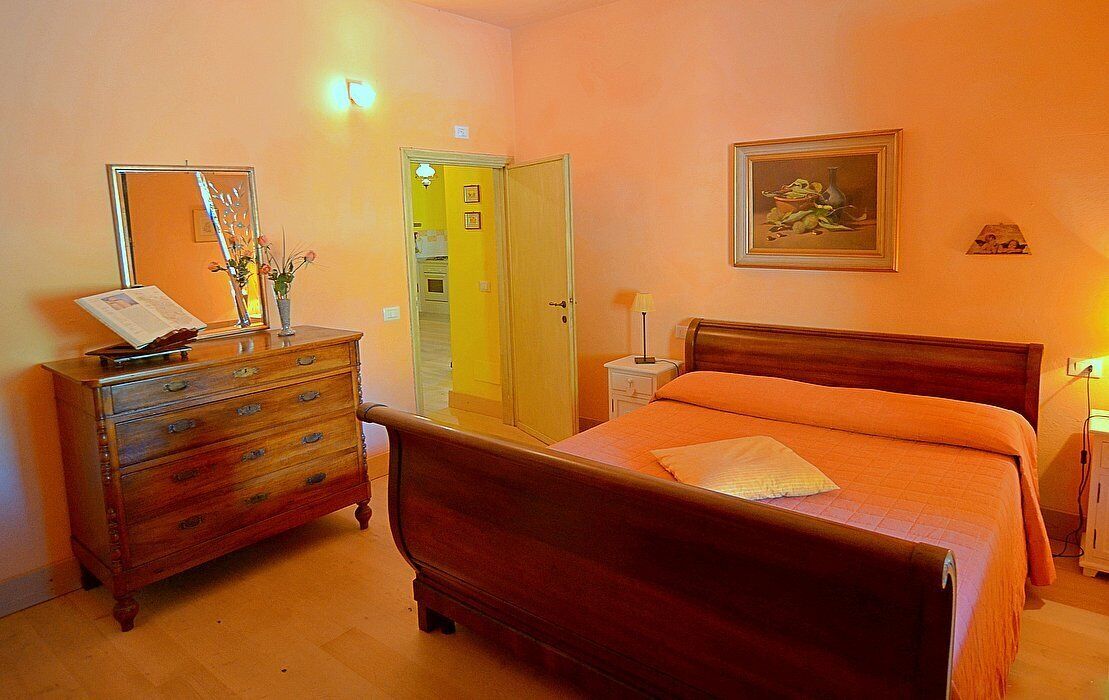 A bedroom with a wooden bed, a dresser, a mirror, and a painting on the wall.