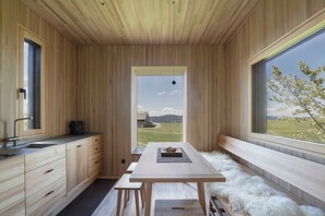 A modern kitchen with wooden cabinetry, a large window, and a view of the countryside. - Adventure tree house, Baldauf family - Tree house (Sulzberg)