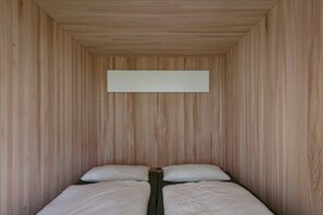 A room with wooden panel walls, two beds with white bedding, and a horizontal light fixture. - Adventure tree house, Baldauf family - Tree house (Sulzberg)