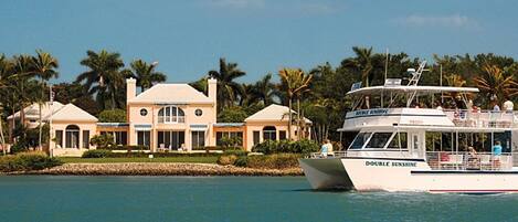 A large house with a pool and a boat named 'DOUBLE SUNSHINE' in the background.