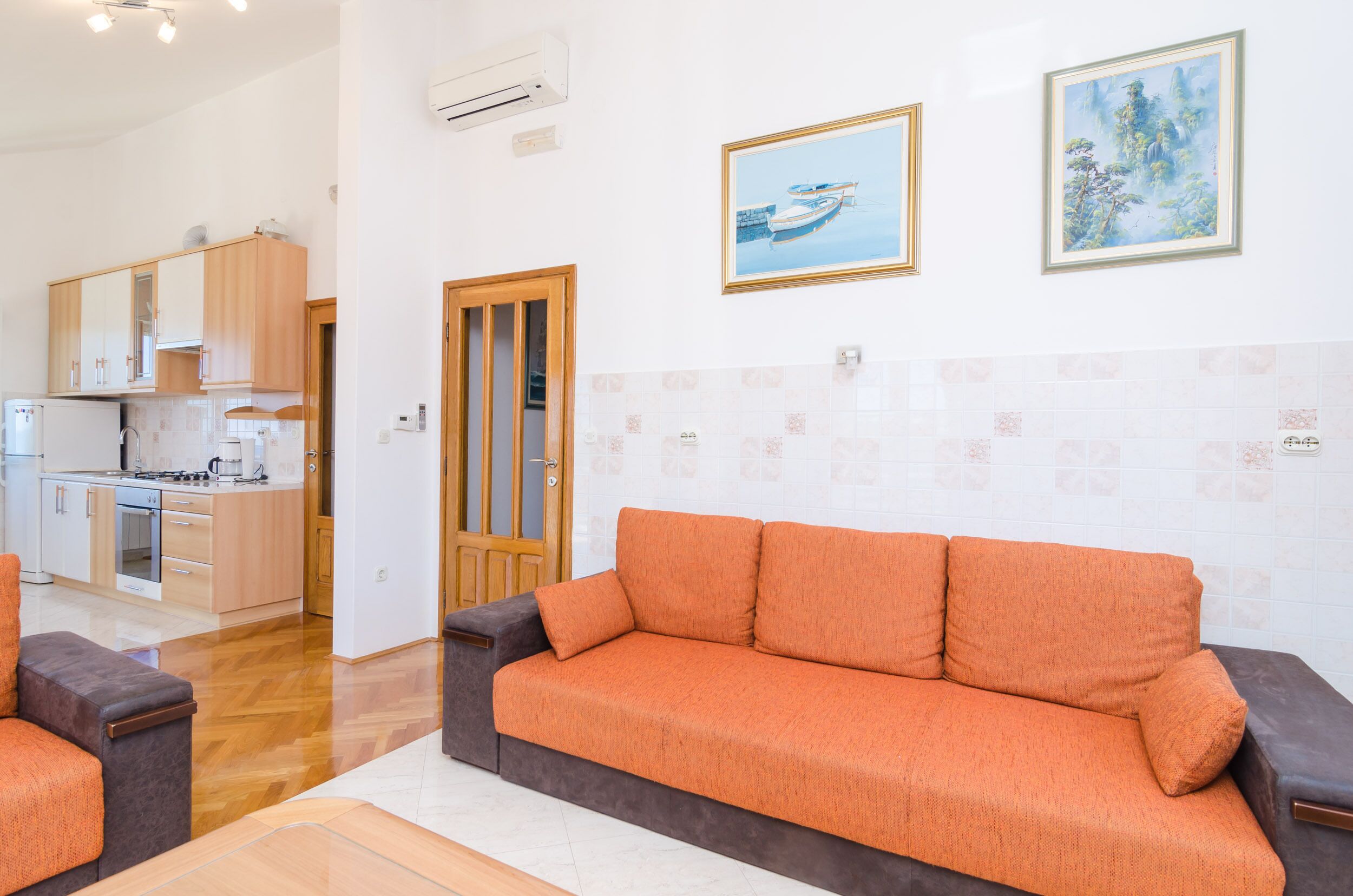 Un salón moderno con un sofá, una mesa de centro y una cocina visible al fondo.