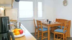 A compact kitchen with a wooden table and chairs, a kettle, and a fruit bowl. - Baltic Sea vacation in an old granary (Heringsdorf)