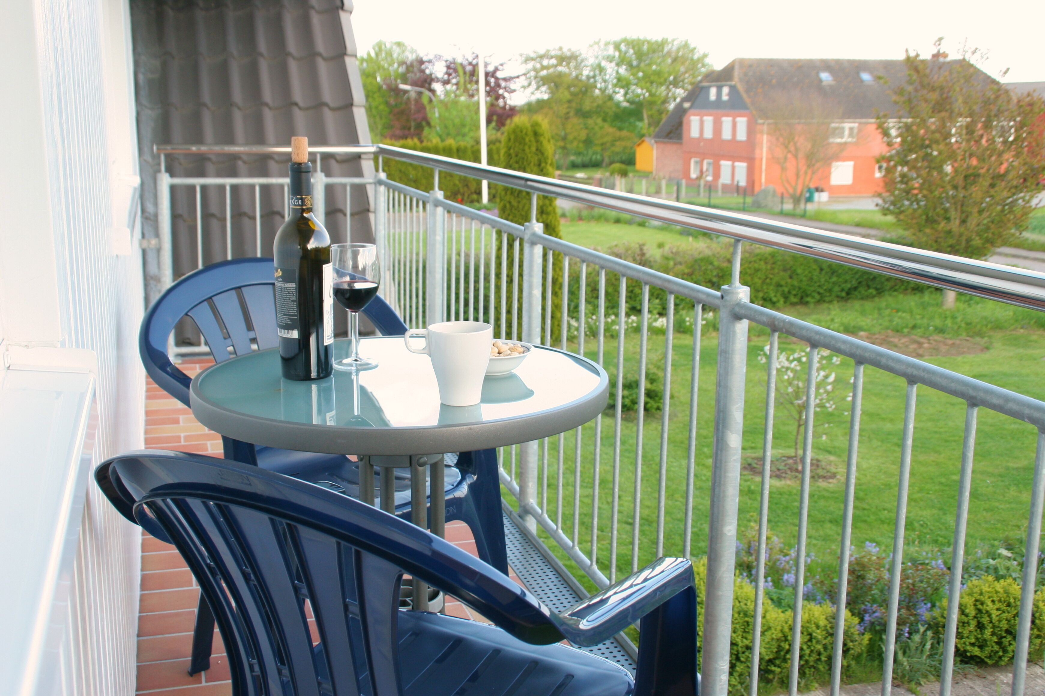 A balcony with a table and chairs, a bottle of wine, and a glass.