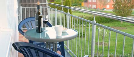 A balcony with a table and chairs, a bottle of wine, and a glass.