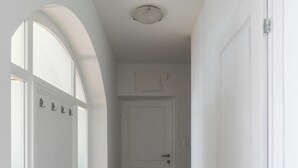 A hallway with a white door, a window with a white frame, and a light fixture on the ceiling. - Apartment Med (Dubrovnik)