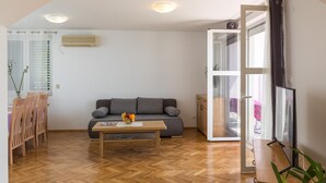 A modern living room with a sofa, a wooden coffee table, and a TV stand. - Apartment Med (Dubrovnik)