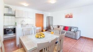 A compact living space with a kitchen, dining area, and a gray sofa with red cushions. - Apartment Budimir (Supetar)