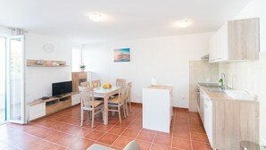 A compact kitchen with a dining area, a TV, and a small island. - Apartment Budimir (Supetar)