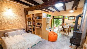 Un dormitorio acogedor con una cama grande, una estantería, un escritorio de madera y una zona de cocina con estufa.