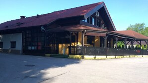 A two-story building with a sloped roof, large windows, and a covered porch area. - Guesthouse Urša (Preddvor)
