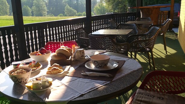 A breakfast setup with croissants, pastries, and coffee on a table with a view of a green field. - Guesthouse Urša (Preddvor)