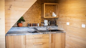 A compact kitchen with wooden cabinets, a marble countertop, a sink, a toaster, and a shelf with glassware and cups. - Apartments Zvoh, Krvavec, Ski-in, Ski-out (Cerklje na Gorenjskem)
