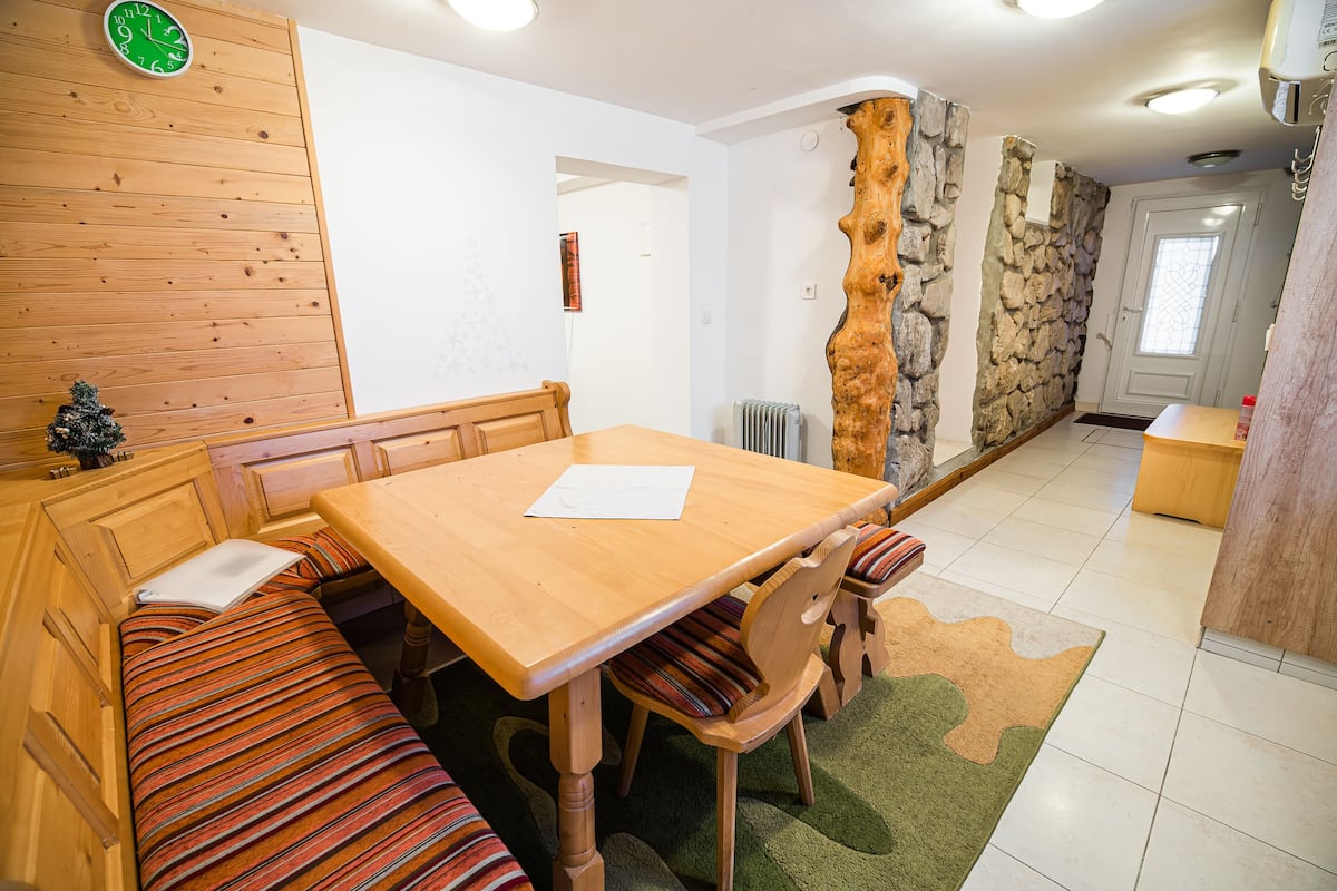 Ein Holztisch mit Bänken, einer Uhr und einer Steinwand.