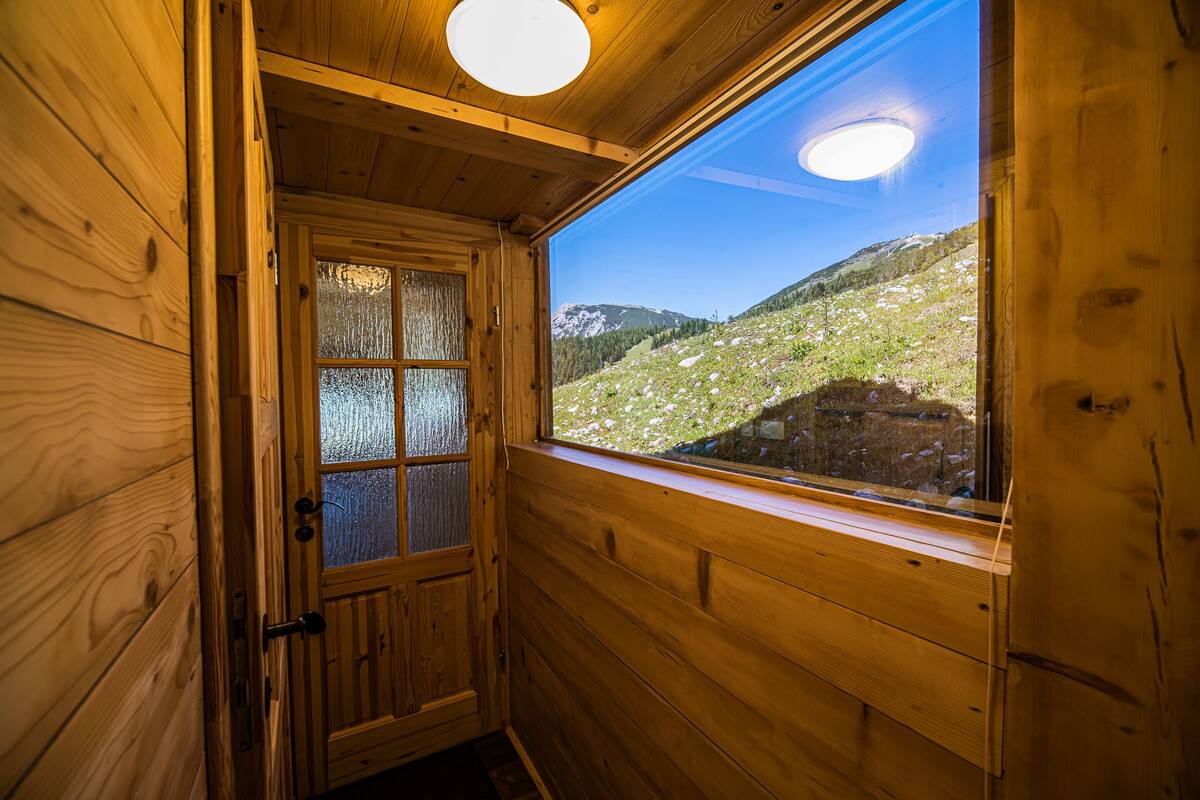 Eine Holzhütte mit einem großen Fenster und Blick auf die Berge.