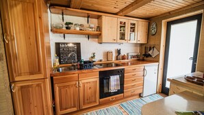 Eine Holzküche mit eingebauten Schränken, einem schwarzen Ofen und einer Tafel mit Küchentipps.