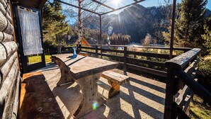 Eine Holzterrasse mit Bank und Tisch mit Blick auf eine gebirgige Landschaft.