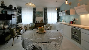 A modern kitchen with a dining area, featuring a round table, chairs, and pendant lighting. - Charming Renovated House, Close to Shops and Beach, La Tranche-sur-Mer (La Tranche-sur-Mer)