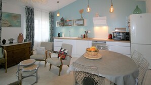 A compact kitchen with a dining area, featuring a round table, chairs, and a variety of appliances including a microwave and refrigerator. - Charming Renovated House, Close to Shops and Beach, La Tranche-sur-Mer (La Tranche-sur-Mer)