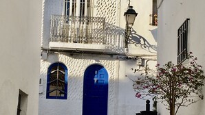 A narrow street with white buildings, a blue door, and a small balcony with a metal railing. - Spacious duplex, beautiful view of the golf course and sea. 120 m2. 5 mn from the beach  (Altea)