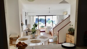 A dining area with a round table, a bowl of fruit, and a potted plant. - Spacious duplex, beautiful view of the golf course and sea. 120 m2. 5 mn from the beach  (Altea)