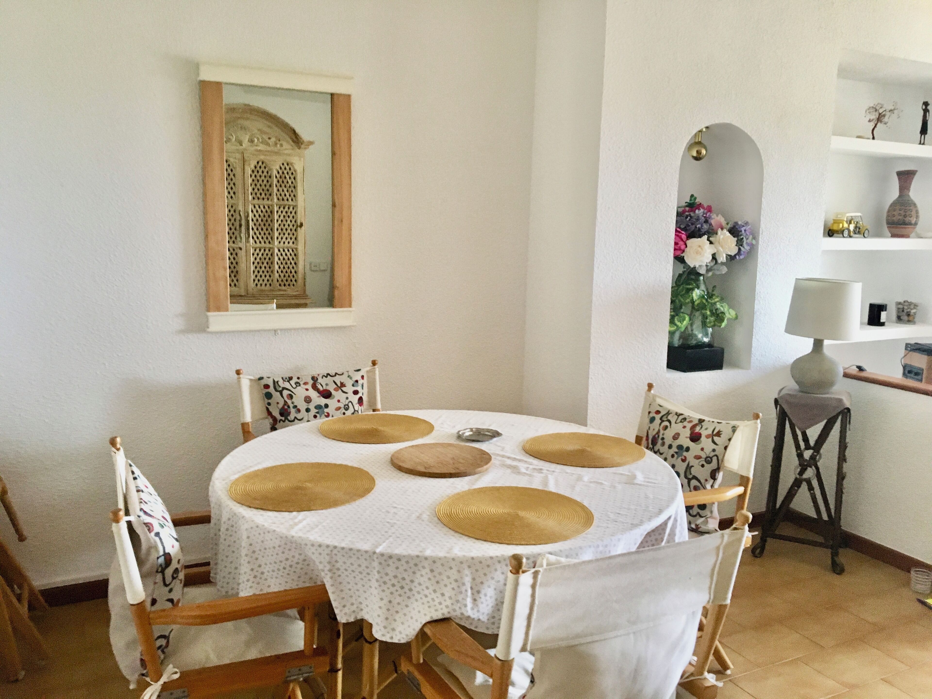 A dining area with a round table, chairs, and a white tablecloth.