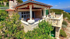 A stone house with a tiled roof, a covered porch, and a view of the sea. - Stone House Horizont (Vela Luka)