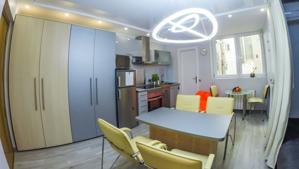 Une cuisine moderne dotée d’un coin repas, comprenant un grand meuble de rangement, un réfrigérateur et une table à manger avec des chaises.