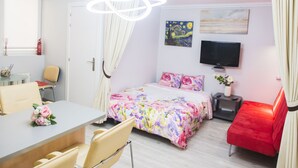 Une chambre d’hôtel moderne équipée d’un lit, d’un bureau, d’une chaise, d’une télévision et d’un canapé rouge.