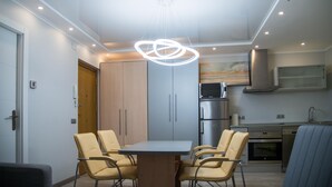 Une cuisine moderne  équipée d’un four encastré, d’un four à micro-ondes et d’appareils électroménagers en acier inoxydable. On y trouve un coin repas avec une table et des chaises, ainsi qu’un luminaire au plafond.
