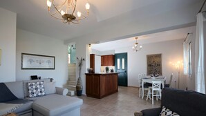 Een ruime woonkamer met een bank, een eettafel en een keuken op de achtergrond.