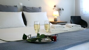 Een netjes opgemaakt bed met twee champagneglazen, een roos en een dienblad in een hotelkamer.