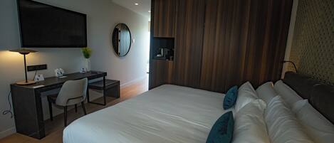 Une chambre d’hôtel moderne dotée d’un grand lit, d’un bureau avec une chaise, d’un téléviseur à écran plat, d’un miroir rond et d’un mur revêtu de panneaux en bois.