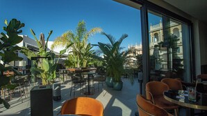 An outdoor seating area with tables and chairs, surrounded by large potted plants, and a view of a historic building in the background. - SOHO BOUTIQUE CATEDRAL (Seville)