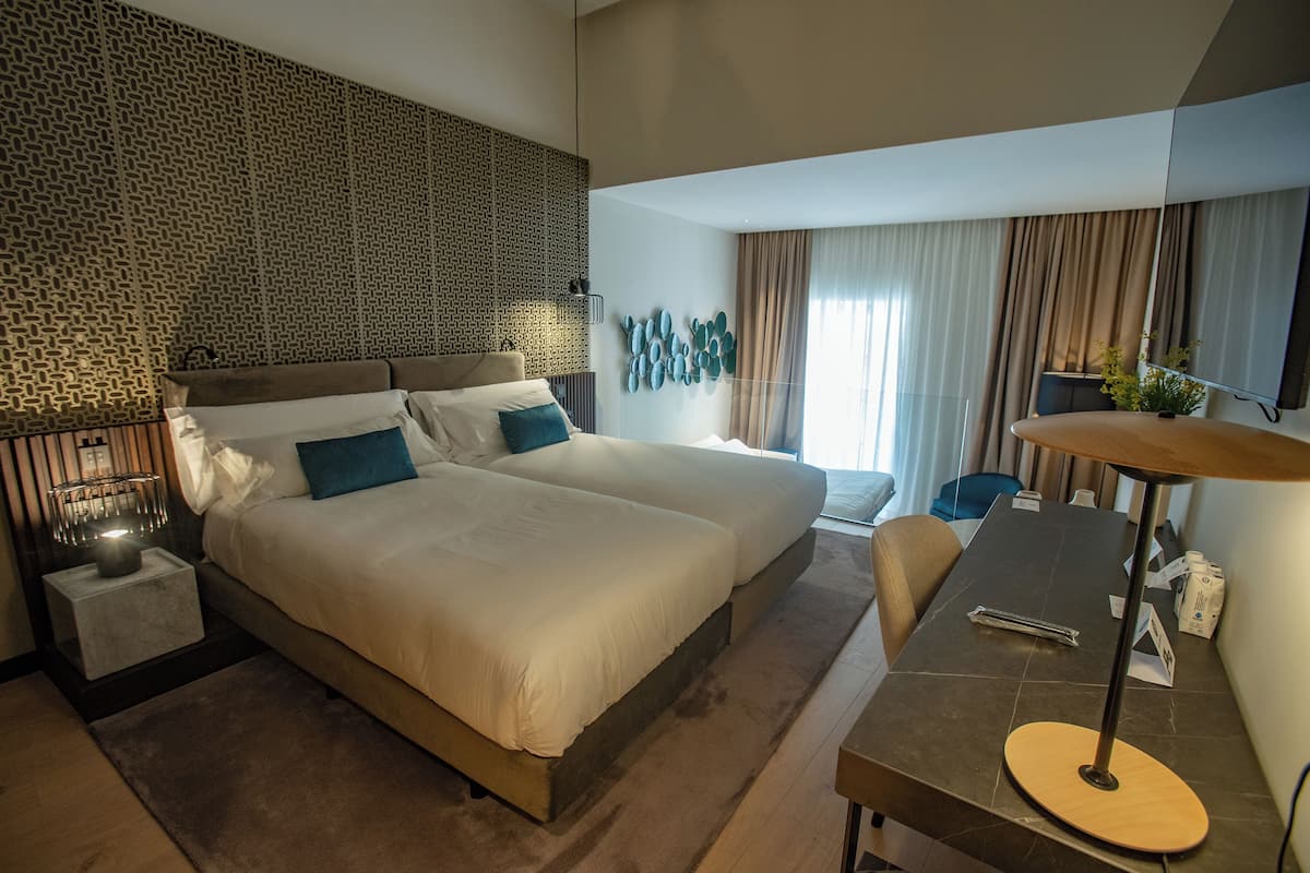 Una habitación de hotel moderna con una cama grande, un escritorio y una zona de estar.
