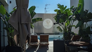 A rooftop terrace with lounge chairs, a table, and potted plants. - SOHO BOUTIQUE CATEDRAL (Seville)