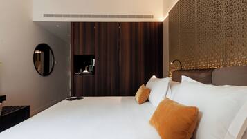 Een moderne hotelkamer met een groot bed, een donker houten garderobe, een ronde spiegel en een behang met een patroon.
