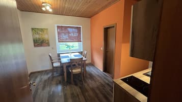 Una habitación con mesa, sillas, ventana con vistas, puerta y zona de cocina con estufa.