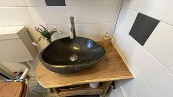 A bathroom with a black stone sink, wooden countertop, and white tiled walls.