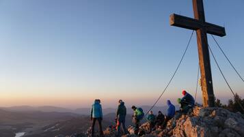 A group of hikers on a mountain with a wooden cross in the background.