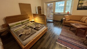 Une pièce confortable avec un lit en bois, un canapé et une fenêtre équipée de stores.