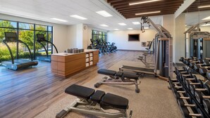 Un gimnasio con cintas de correr, máquinas de pesas y mancuernas.
