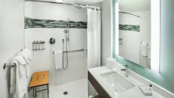 Uma casa de banho moderna com chuveiro, pia e espelho.