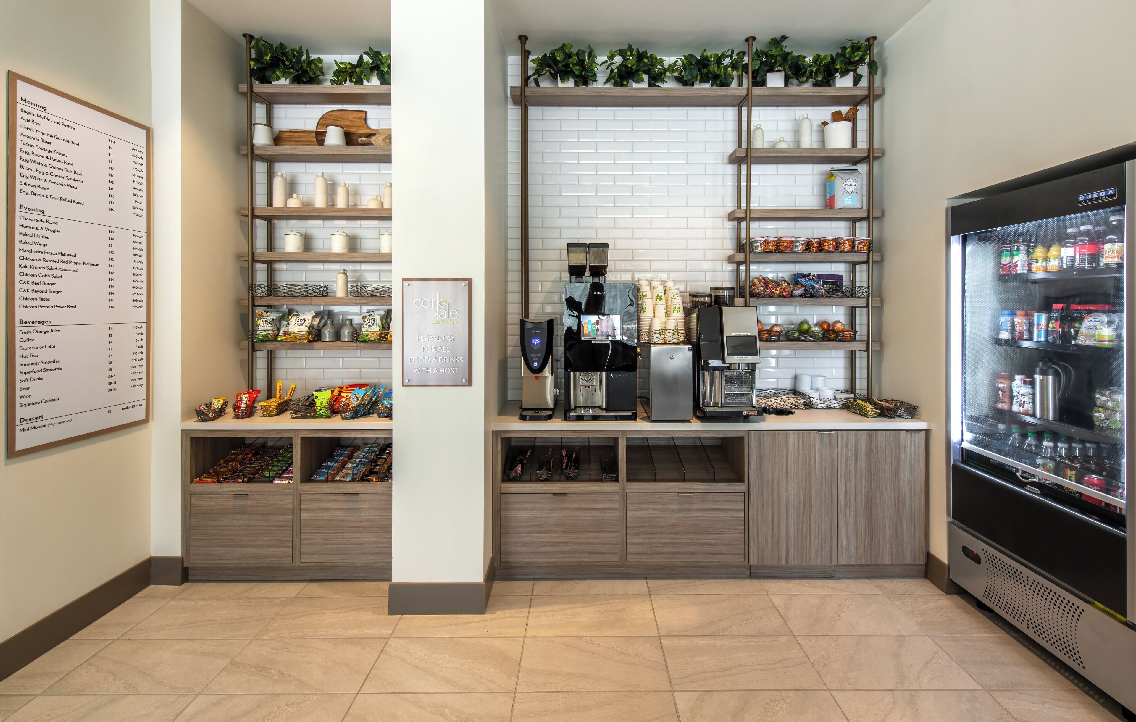A self-service beverage station with a menu board, shelves with snacks, and a refrigerated display.