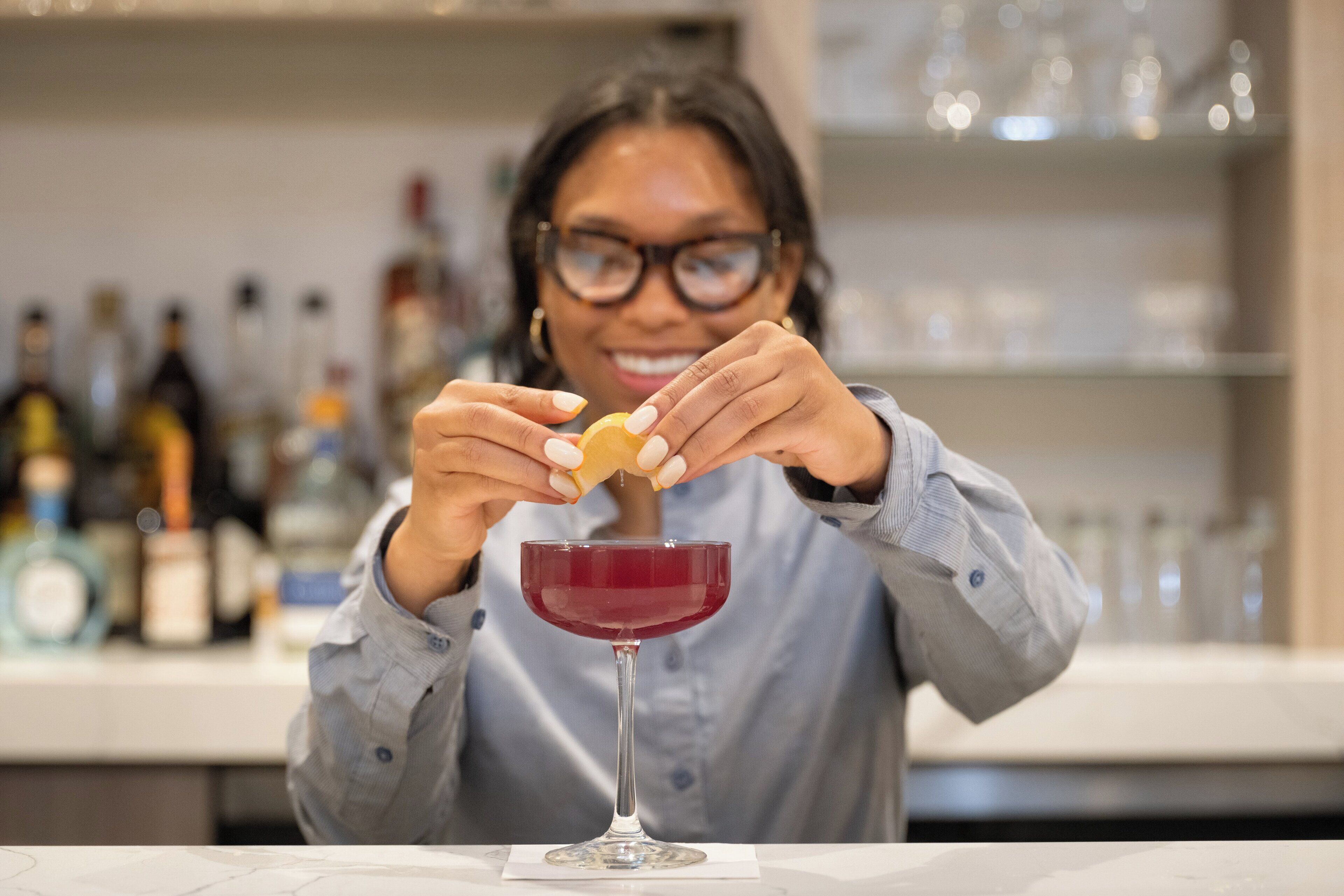 A person pouring a red liquid into a glass with a stem.