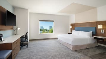 A hotel room with a bed, desk, chair, and a TV mounted on the wall.