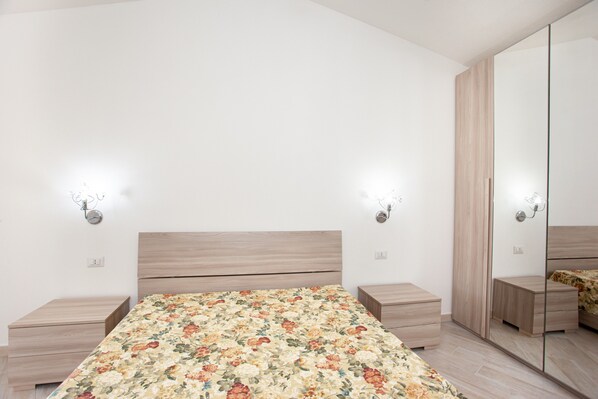 Ein Schlafzimmer mit einem Bett, Nachttischen, einem Spiegel und Wandleuchten.