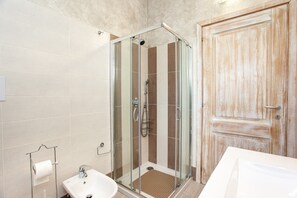 Un baño con ducha de vidrio, lavamanos y puerta de madera.