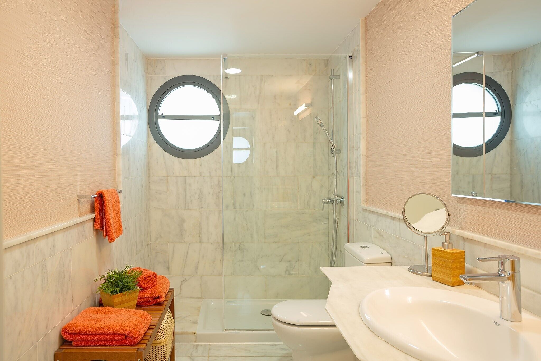 A bathroom with a glass-enclosed shower, a toilet, a sink with a mirror, and a towel rack.